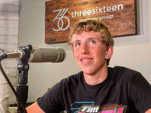 young man sitting at a table with a podcast microphone