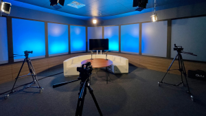 modern podcast studio with a couch, tv, table and three cameras