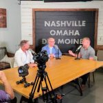 Three middle aged white men speaking into podcast microphones while sitting in a podcast studio in Omaha