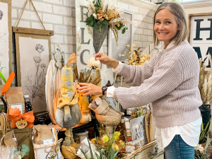 a white women with grey hair and a sweater is working in a gift shop