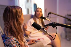 two women on podcast microphones