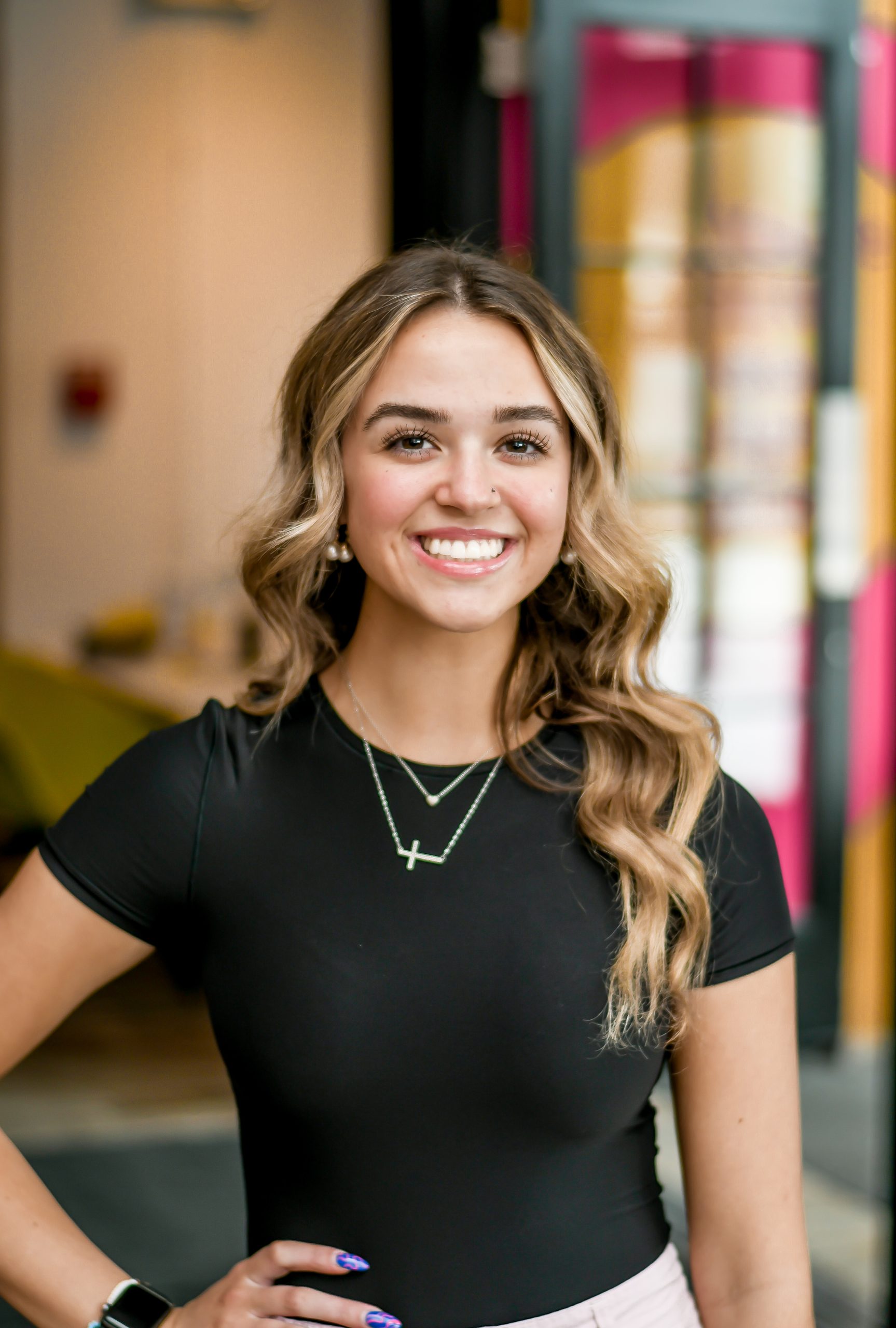 a visual content creator wearing a black shirt and a cross necklace.
