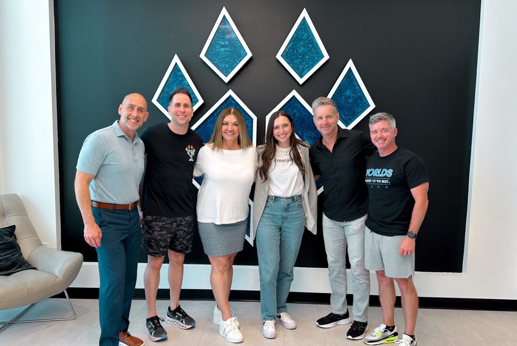 a group photo of two woman and four men at a cheer gym. 
