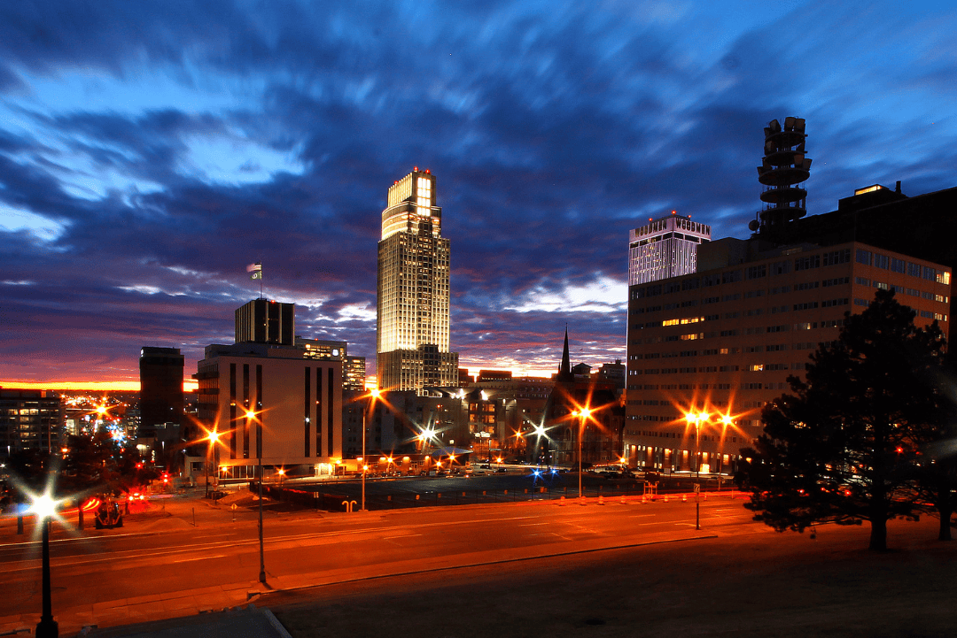 A city skyline illuminated by lights during twilight hours.