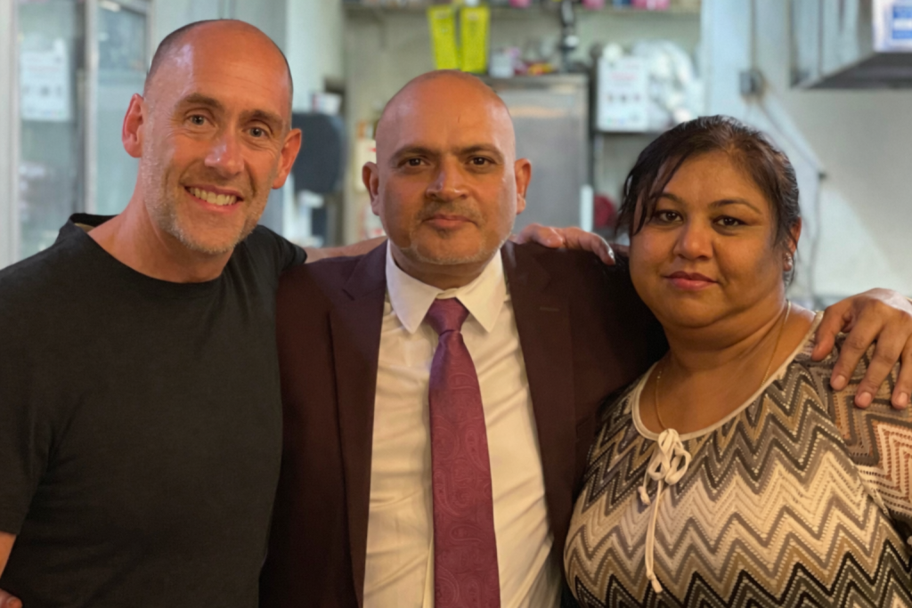Restaurant owners meeting with a hospitality marketing consultant inside a working kitchen