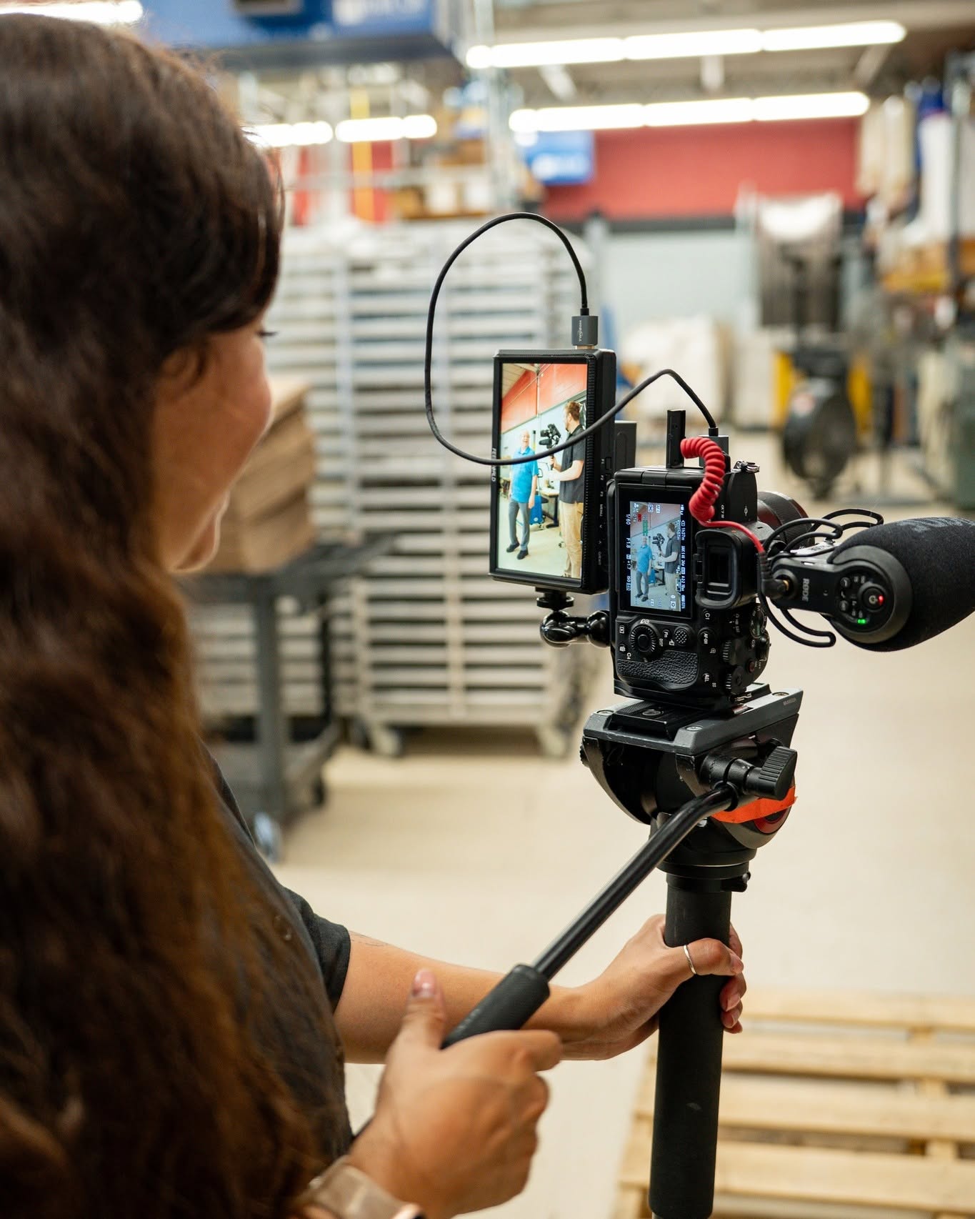 Behind the scenes at 316 Strategy Group in Omaha, a hairdresser prepares a model for a video shoot while interacting with the camera crew.